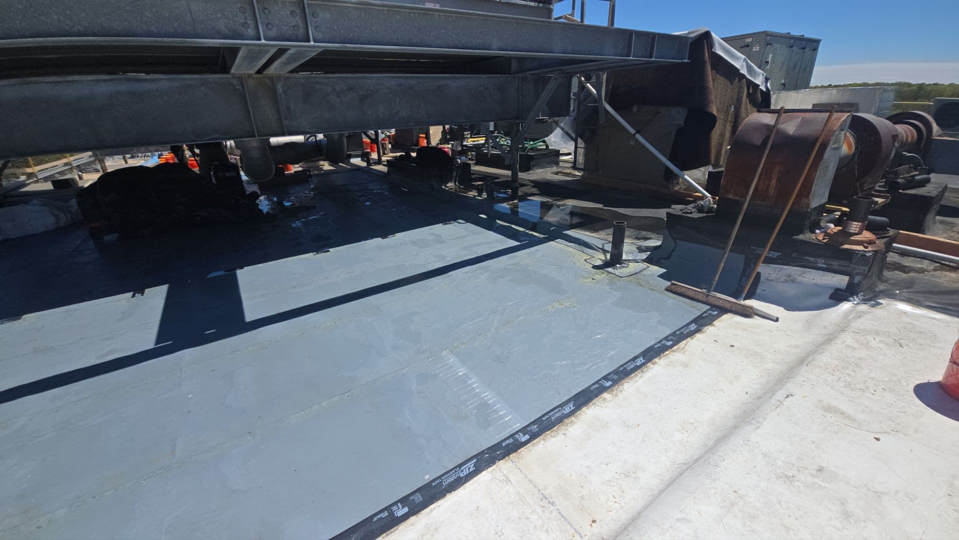 Prepared roofing surface fitted around steel supports and penetrations beneath an elevated mechanical platform