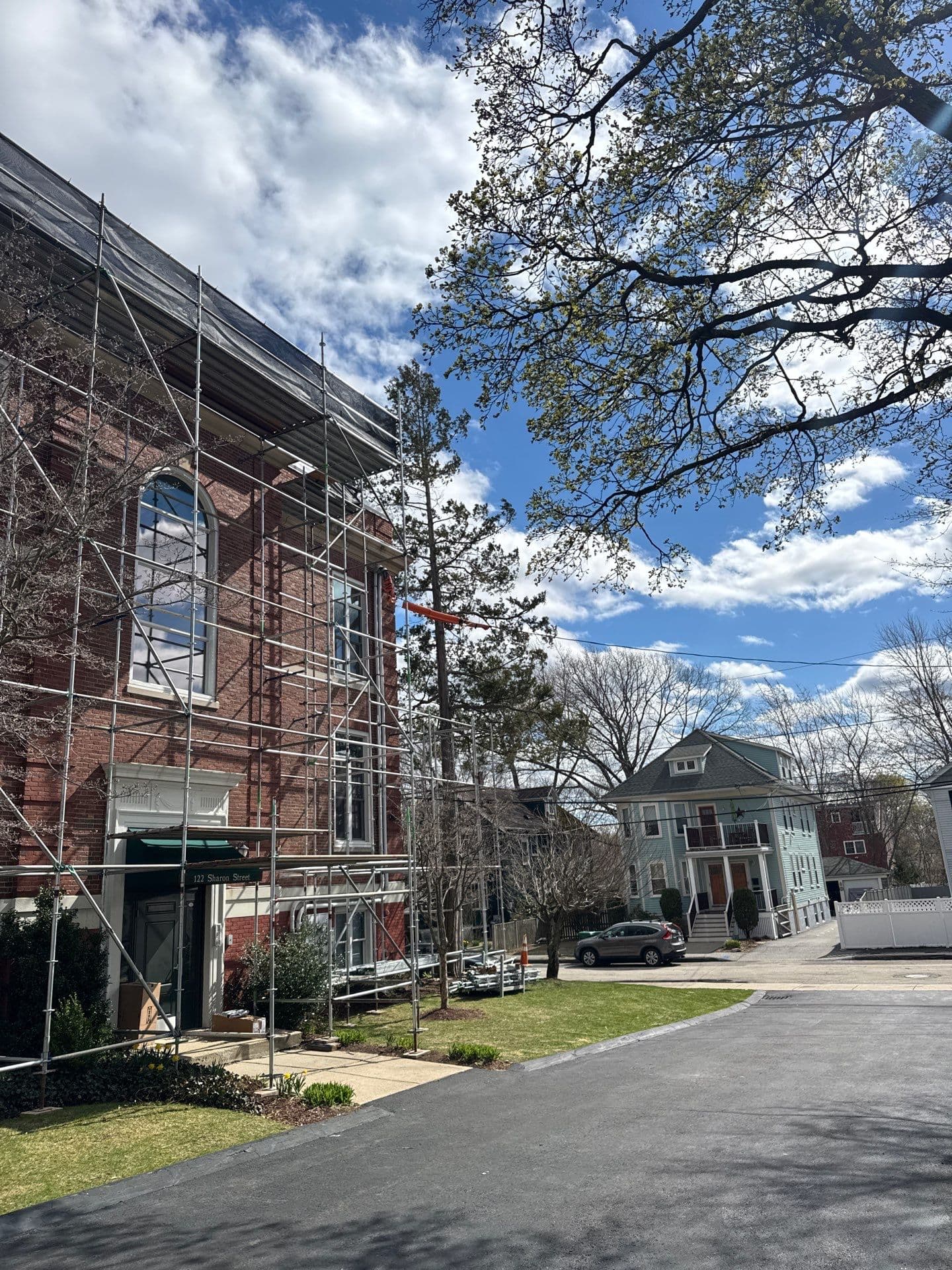 Street-level view of scaffold running along the brick entrance facade at 122 Sharon Street