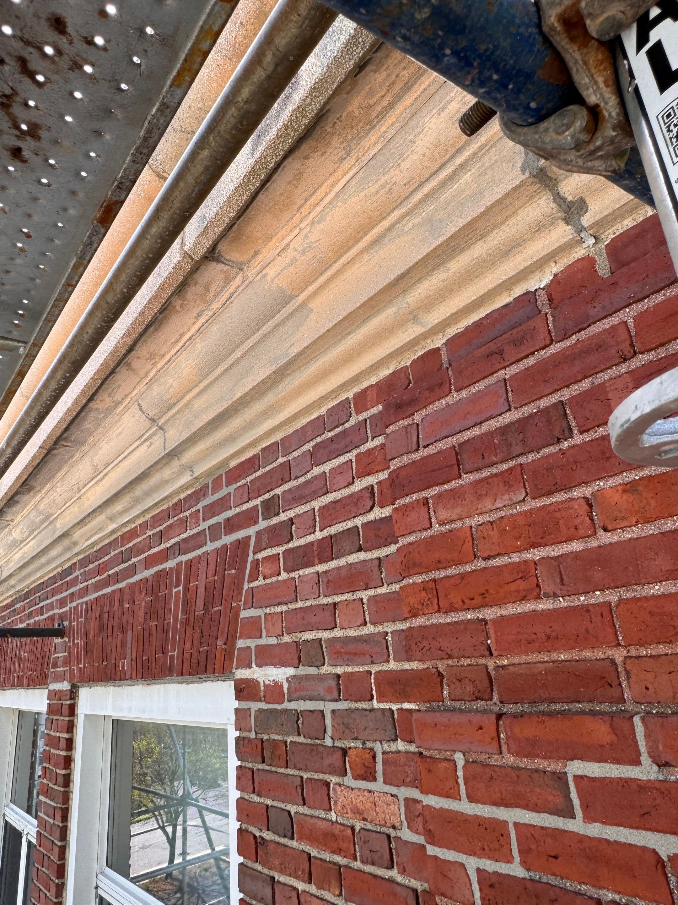 Existing brick facade, window head, and cornice viewed from the scaffold platform