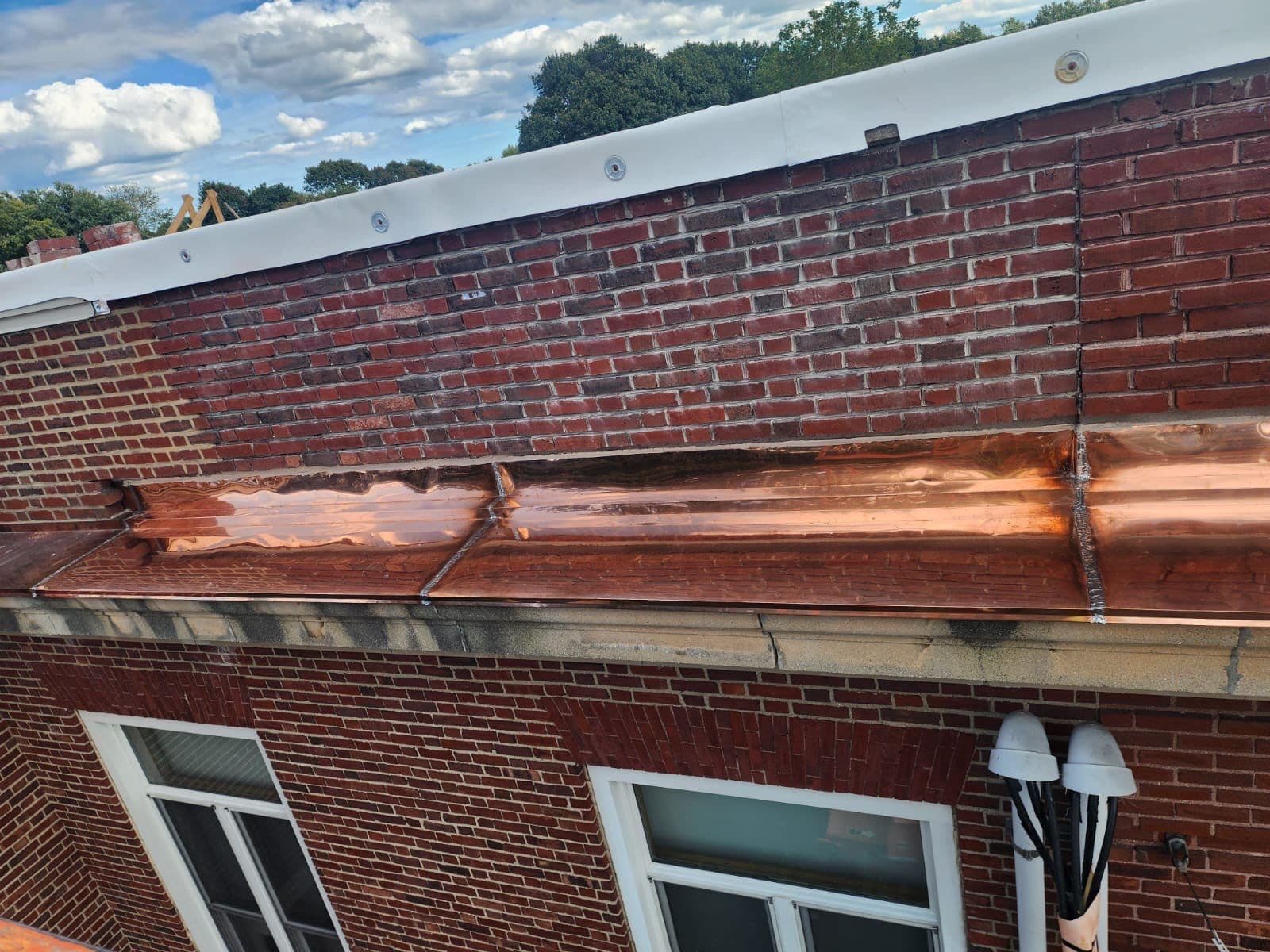Wide view of copper flashing running along the brick parapet above windows at 122 Sharon Street