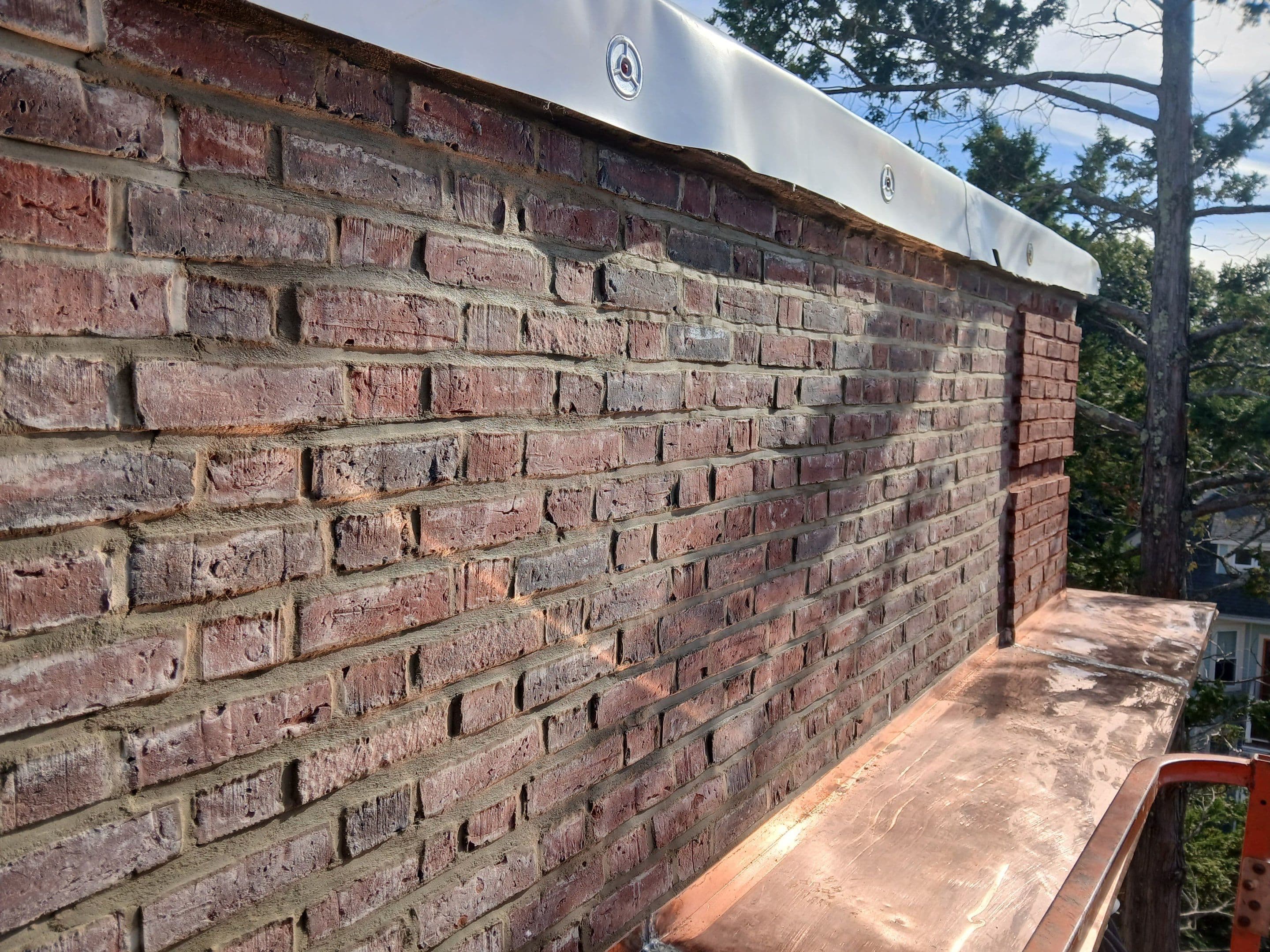 Wide view along the brick parapet and copper flashing on the exterior ledge at Sharon Street