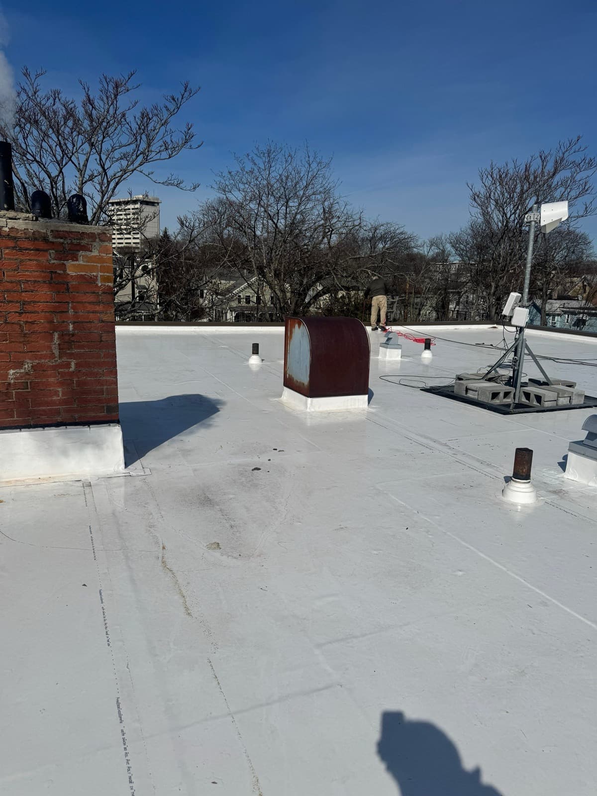 Membrane flashings around a brick chimney, vents, and rooftop penetrations
